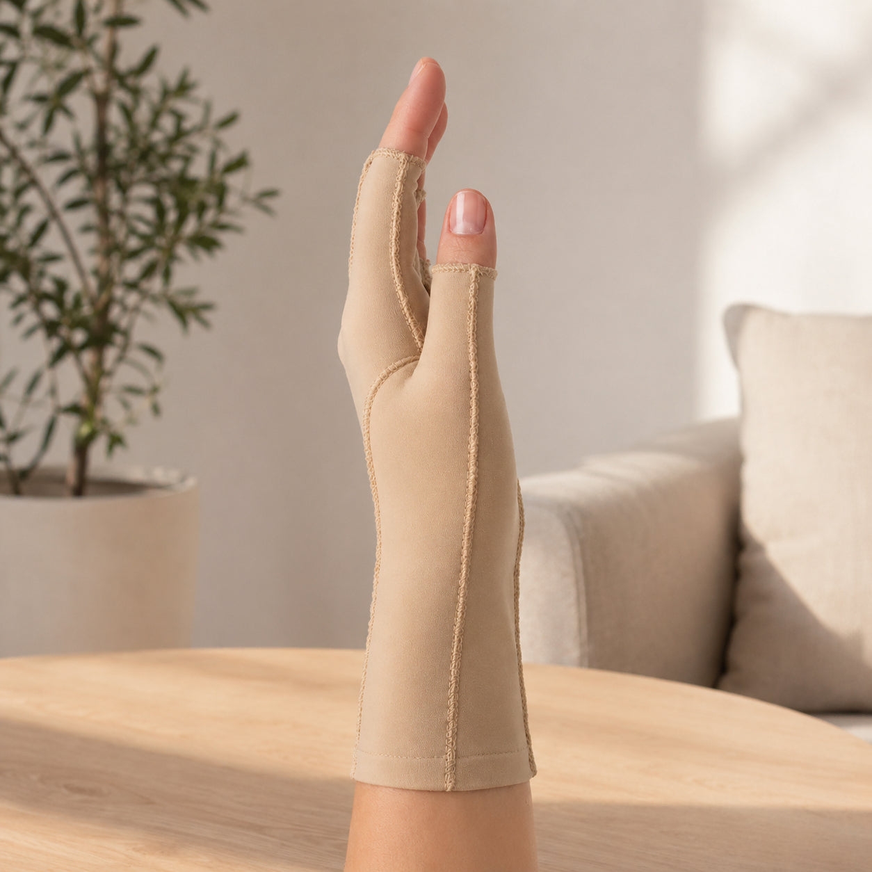 Beige kompressionshandske med öppna fingertoppar som ger stöd för hand, tumme och handled.