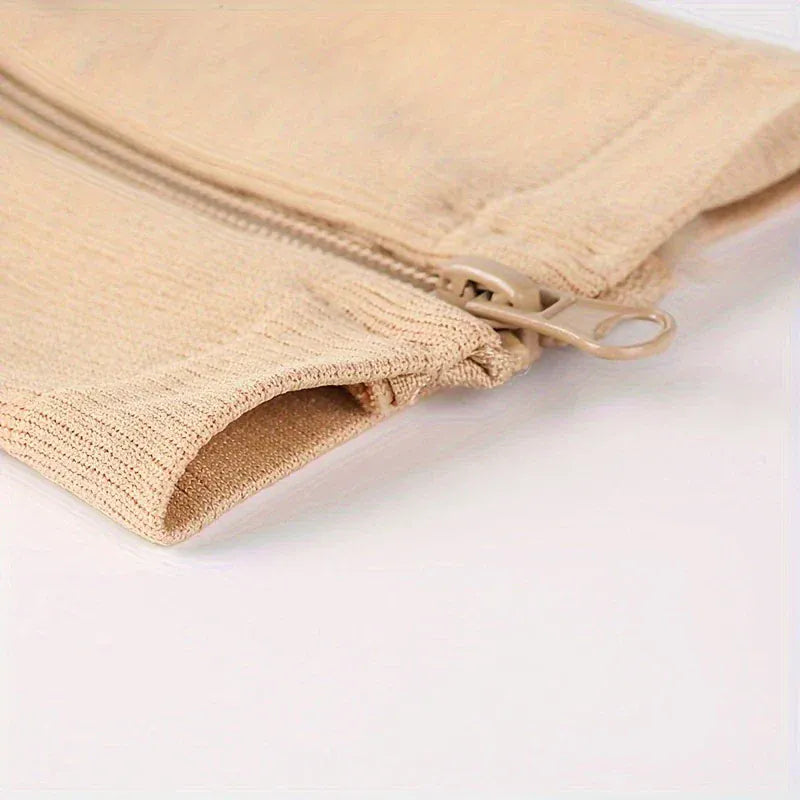 Närbild på dragkedjan och öppningen på beige stödstrumpor, visar enkel på- och avtagning.