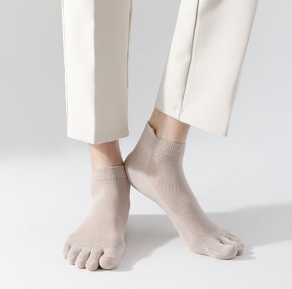 Person står på ljus bakgrund med tunna tåstrumpor i mjukt, följsamt material som separerar tårna och sitter tätt runt foten